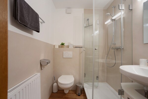 Une salle de bain moderne équipée de toilettes, d’un bidet et d’une douche à parois de verre.
