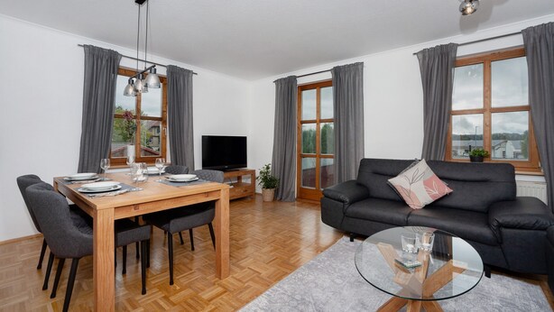 Een moderne woonkamer met een eettafel, bank en televisie.