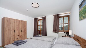 Een slaapkamer met twee bedden, een houten garderobe, een raam met gordijnen en een radiator.