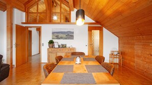 A dining area with a wooden table, chairs, and a hanging light fixture.
