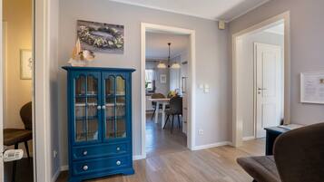 A hallway with a blue cabinet, a dining area, and a door leading to another room.