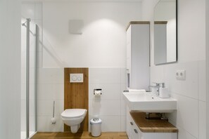 Et moderne badeværelse med toilet, bidet, vask, spejl og bruser.