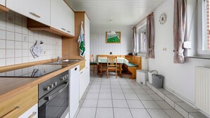 Une cuisine avec un plan de travail en bois, une cuisinière, un évier et un coin repas comprenant une table et des chaises.