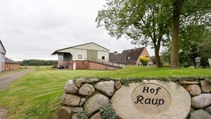 Un mur de pierre sur lequel est fixée une plaque portant l’inscription « Hof Raup », avec un bâtiment en arrière-plan.