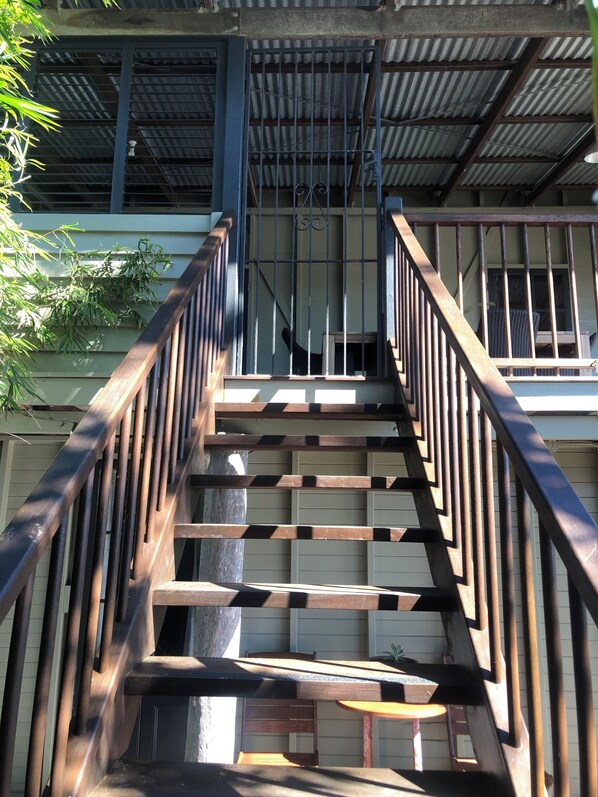 Una escalera de madera con barandales de metal que conduce a la entrada de un edificio.