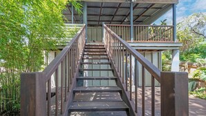 Eine Holztreppe führt zu einem überdachten Außenbereich mit Metallgeländern.