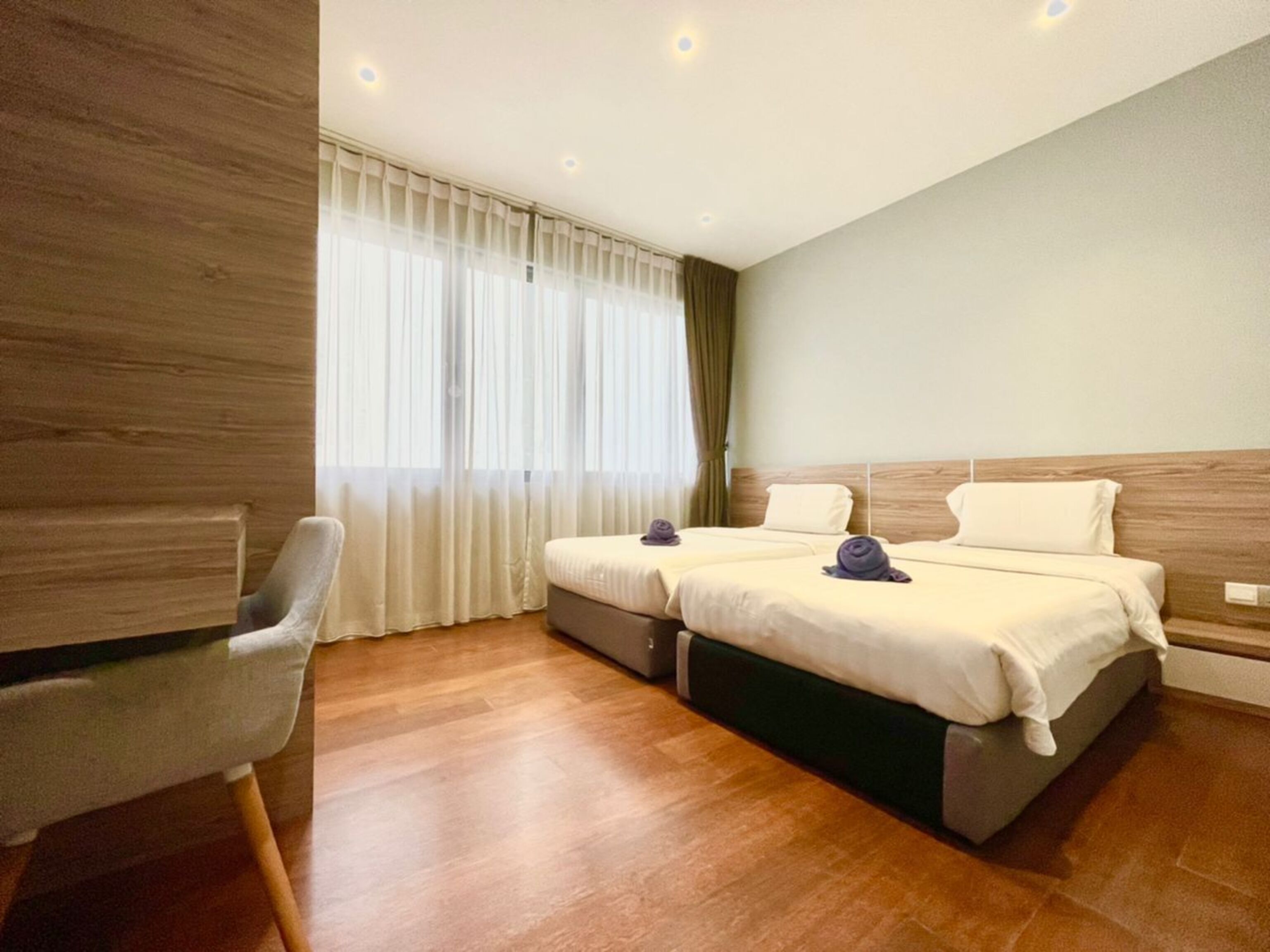 Een hotelkamer met twee bedden, een houten hoofdeinde, een bureau en een stoel.