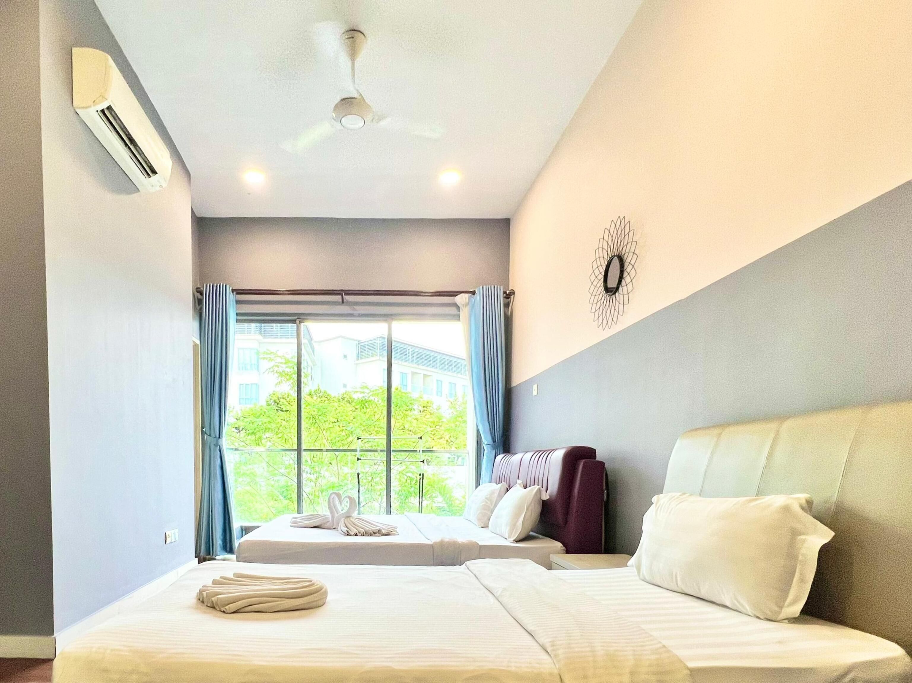 A hotel room with two beds, a ceiling fan, and a view of greenery outside.