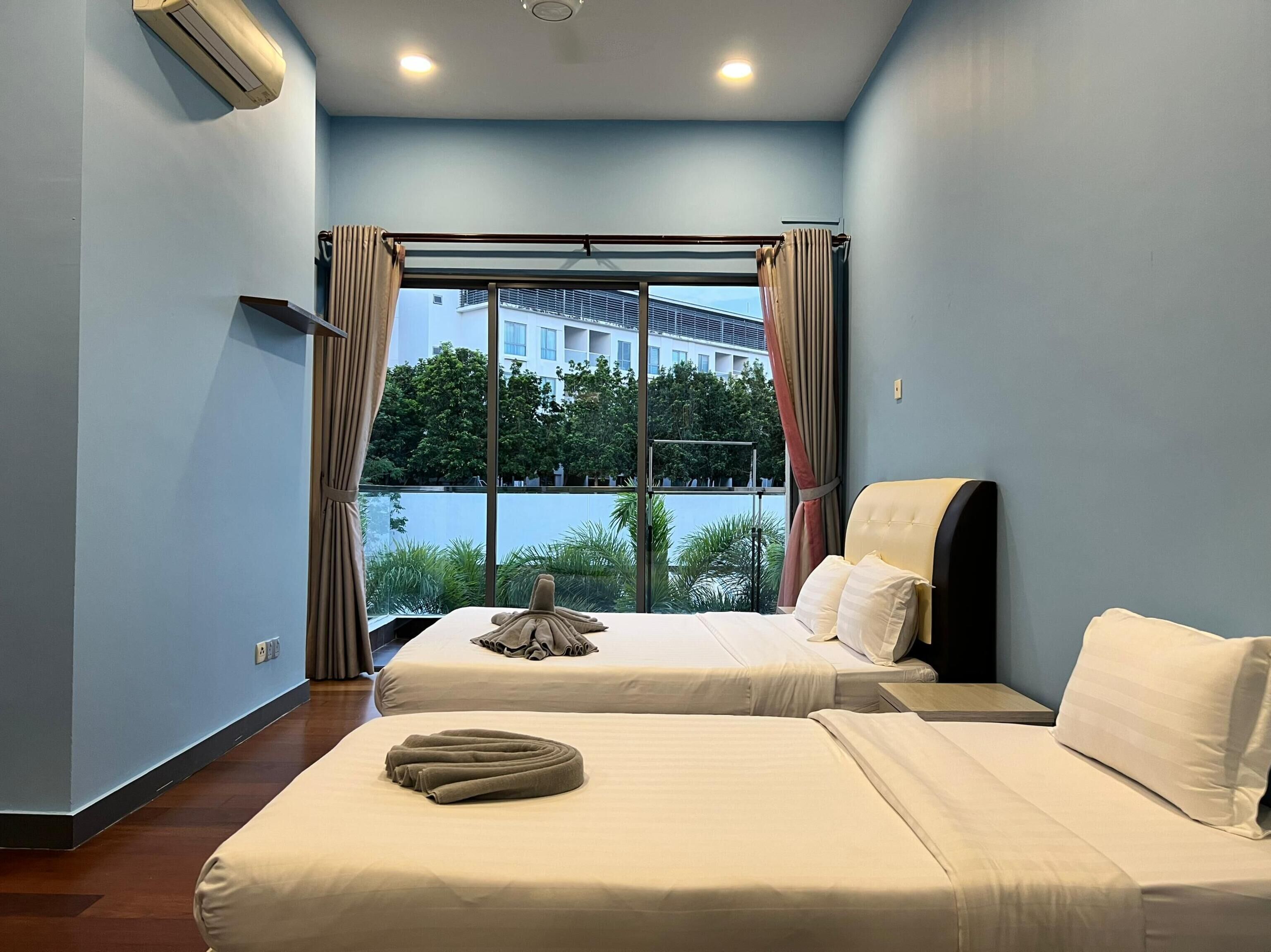 A hotel room with two beds, a large window with curtains, and an air conditioning unit on the wall.