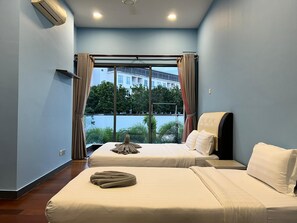 Une chambre d’hôtel avec deux lits, une grande fenêtre avec des rideaux et un climatiseur fixé au mur.