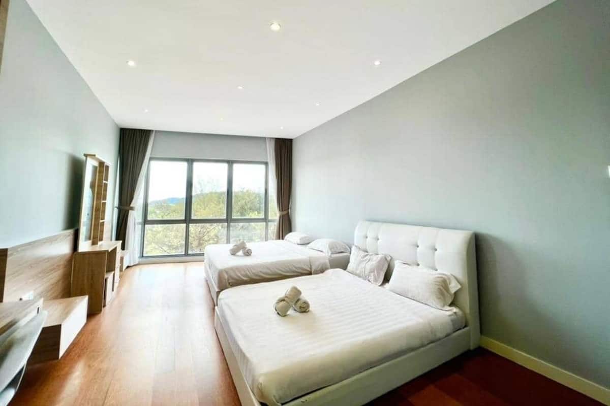 A modern hotel room with two beds, a large window, and a wooden bench.