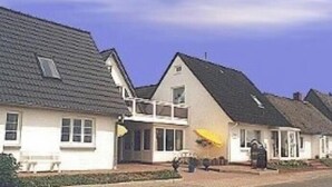 A row of white houses with grey roofs, a small porch, and a bench. - Apartment 'Bi Reiner' with Private Terrace and Wi-Fi (Nordstrand)