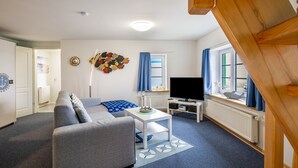 A living room with a sofa, TV, and a decorative wall piece. - Apartment 'Bi Reiner' with Private Terrace and Wi-Fi (Nordstrand)