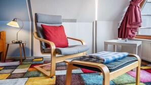 A room with a wooden chair, a small table, a colorful carpet, and a lamp. - Apartment 'Bi Buje' with Balcony and Wi-Fi (Nordstrand)