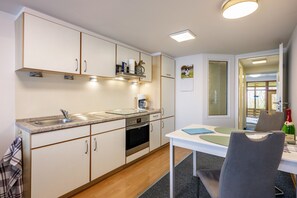 Eine moderne Küche mit Einbauofen, Spüle und Essbereich mit Tisch und Stühlen.
