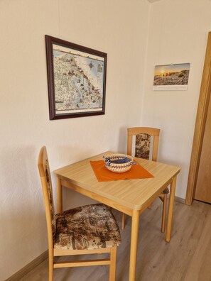 A dining area with a wooden table, chairs, and a framed map on the wall.