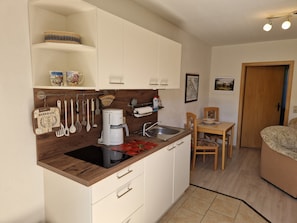 A compact kitchen with a coffee maker, utensils, and a sink.