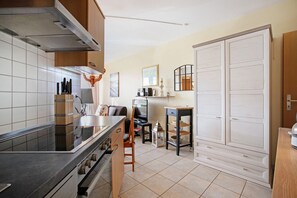 Une cuisine compacte dotée d’un îlot central, d’un four encastré et d’un coin repas avec une chaise et une table.