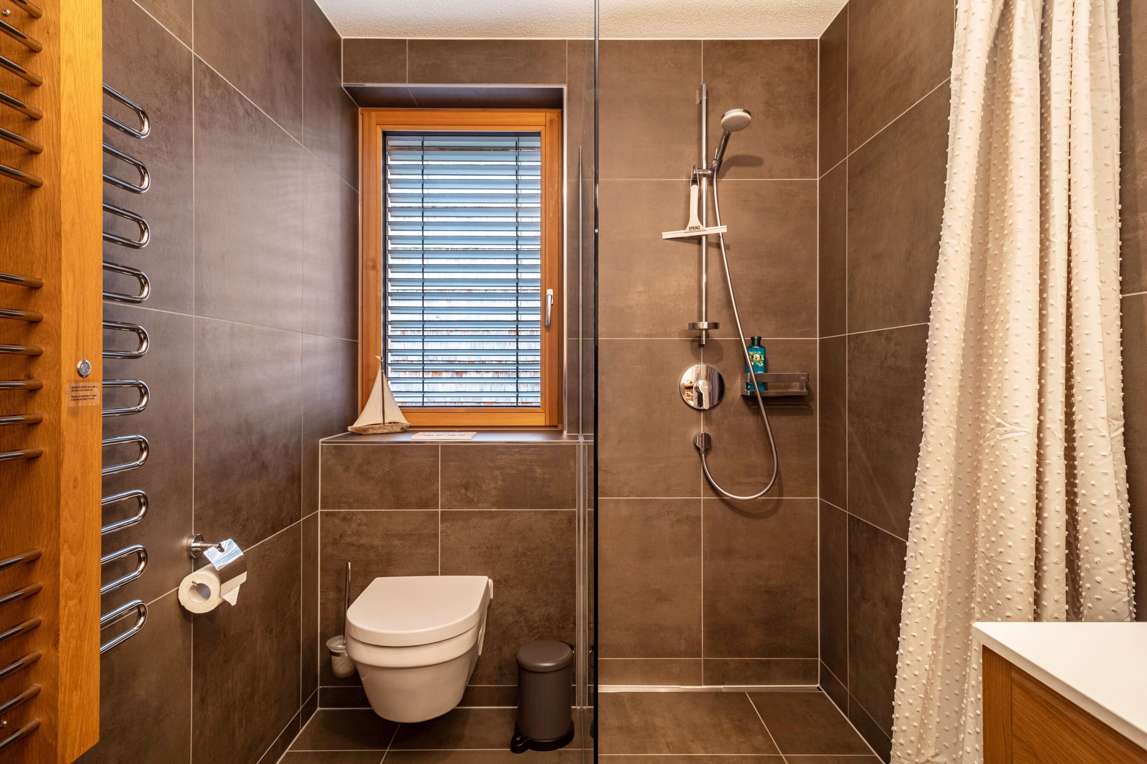 Un baño con inodoro, ducha y ventana.