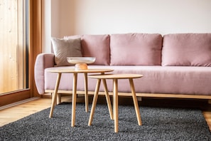 A minimalist living room with a sofa, two small wooden tables, a bowl, and a dark carpet. - Design Apartment Au with Mountain View, Balcony and Wi-Fi (Au)