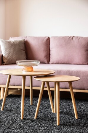 A round wooden table with a bowl on it, placed on a carpeted floor.