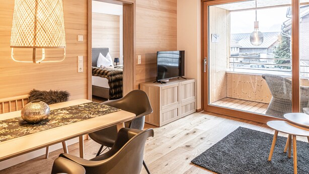 A modern room with a wooden floor, a dining table with chairs, a TV on a cabinet, and a balcony with a view. - Design Apartment Au with Mountain View, Balcony and Wi-Fi (Au)