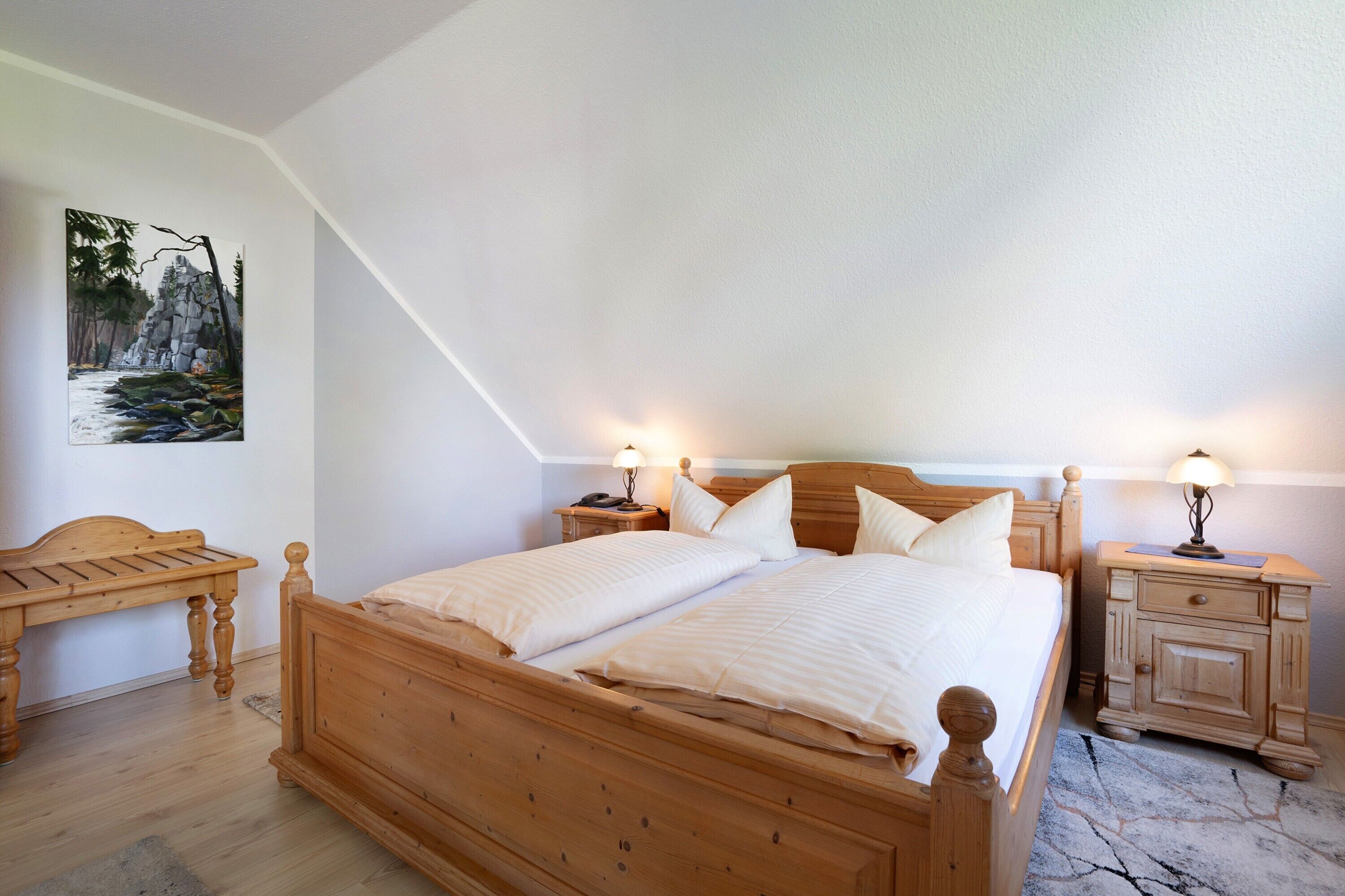 Una camera da letto con un letto di legno, due comodini, una scrivania in legno e un quadro appeso al muro.