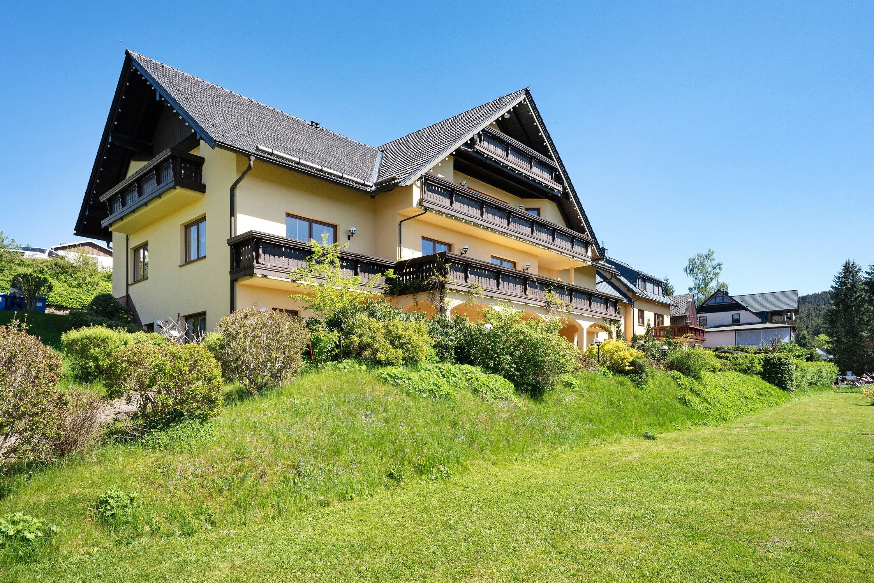 Un grand immeuble à plusieurs étages, doté de balcons et entouré d’une végétation luxuriante.