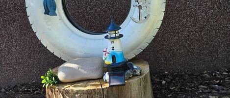Une composition décorative comprenant une maquette de phare posée sur un tronc d'arbre, entourée d'un pneu et de divers petits objets.