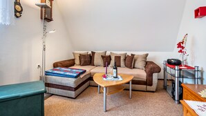 A living room with a sofa, a coffee table, a lamp, a clock, and a small side table with a vase. - Apartment 'Ferienwohnung Auf Der Insel Rügen' with Shared Terrace and Shared Garden (Bergen auf Rügen)