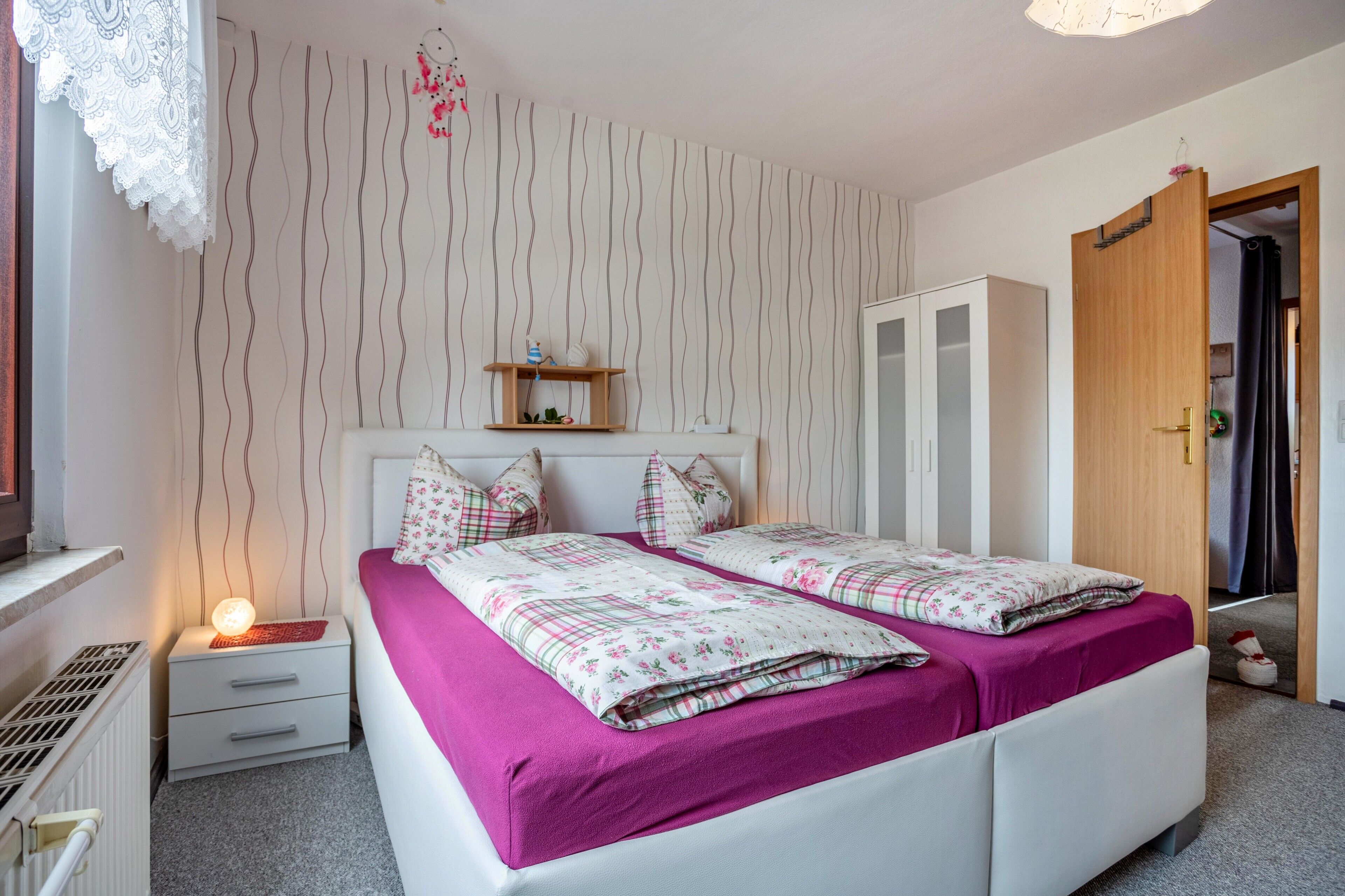 Une chambre avec deux lits, une table de chevet, une commode et une armoire.