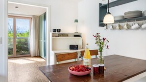 A modern kitchen with a wooden table, a bowl of fruit, a bottle of orange juice, and a vase with flowers. - Apartment 'Schambachhof' (Bötzingen am Kaiserstuhl)