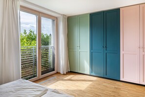 A room with a sliding glass door to a balcony, a bed, and a set of cabinets.