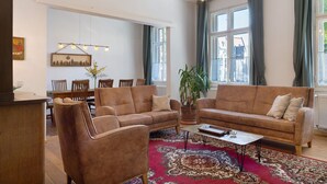 Een woonkamer met een bank, salontafel en een eethoek met stoelen en een tafel.