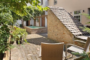 A courtyard with a pool, wicker chairs, and a stone wall.