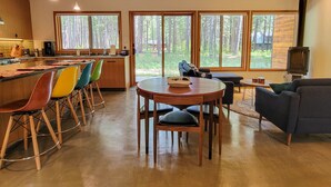 A modern kitchen with a bar area, a dining table with chairs, and a sofa. - Petrichor - Mazama Modern Cabin (Mazama)