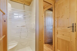 A wooden interior with a glass shower enclosure and a wooden door.