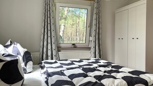 Une chambre à coucher avec un lit, une fenêtre avec des rideaux, un radiateur et une armoire.