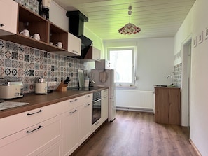 Une cuisine avec des carreaux décoratifs, des armoires en bois, un four encastré et une fenêtre.