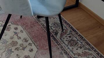 A room with a light blue chair, a wooden table, and a patterned rug.