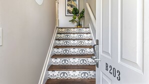 Una escalera con peldaños decorados que conduce a una puerta con el número B203.