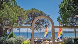 A coastal entrance with a stone archway, boats, and flags.