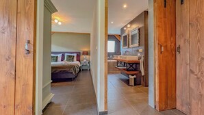 A hotel room with a bed, bedside table, lamp, and a bathroom with a sink and mirror. - Tastefully decorated country villa (Alphen)