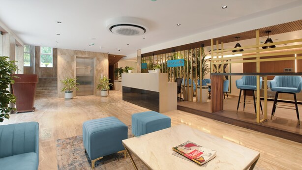 Eine moderne Lobby mit Empfangsschalter, Sitzgelegenheit und einer Treppe zum Aufzug.