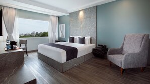 Ein modernes Hotelzimmer mit einem großen Bett, einer Sitzecke und Blick auf die Stadt.