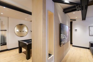 Un interior moderno con mesa de billar, un espejo redondo y televisor de pared.