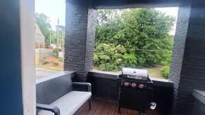 A covered outdoor seating area with a grill and a view of greenery.
