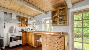 Une cuisine avec des meubles de rangement en bois, une cuisinière et une grande fenêtre.