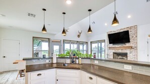 A modern kitchen with white cabinetry, granite countertops, and pendant lighting. - Modern Bryan Farmhouse on 1 Acre w/ Hot Tub! (Bryan)