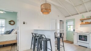 Una cocina con estufa blanca, repisa de madera con adornos y lámpara colgante.
